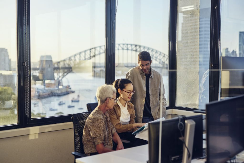Three colleagues collaborating in a Sydney office overlooking the harbour