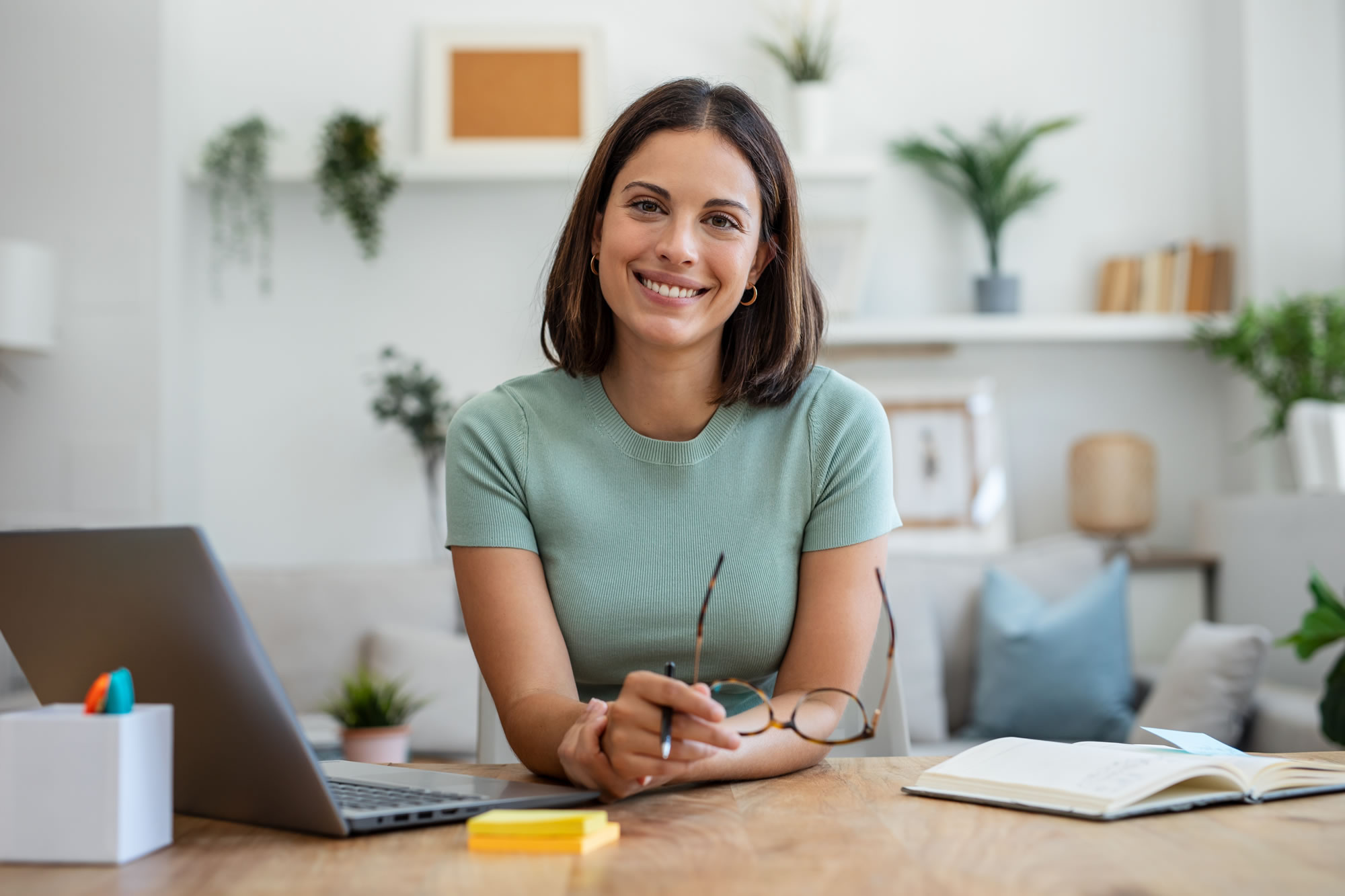Confident woman working from a desk with a laptop and notebook