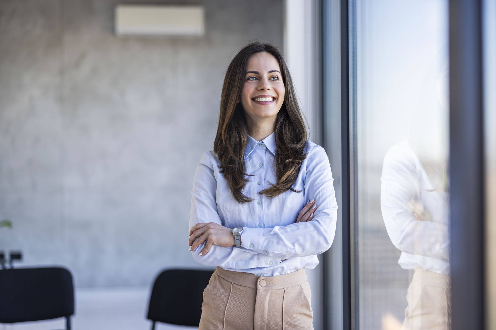 Confident woman leader standing beside an office window