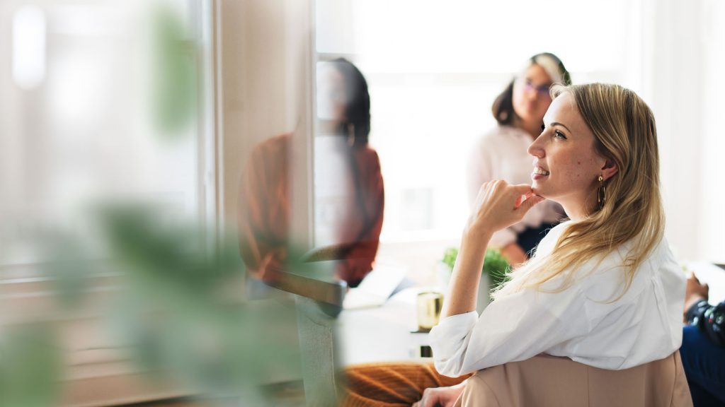 Woman listening and reflecting during a workplace leadership meeting