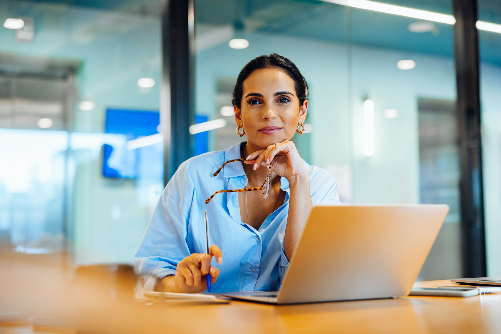 Woman leader reflecting while working at a laptop in a modern office