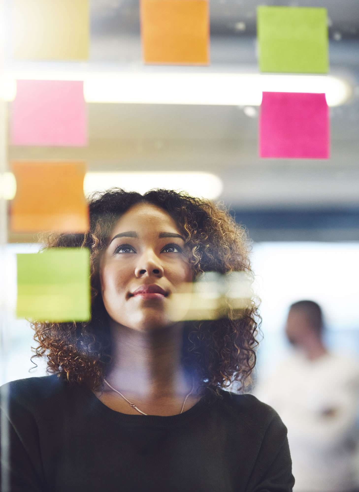 Woman leader reviewing ideas displayed on colourful sticky notes